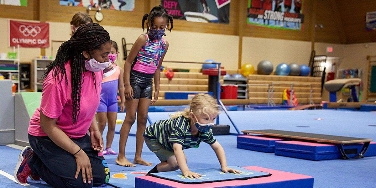 African American female Bolingbrook Park District staff member working with toddler in gymnastics class