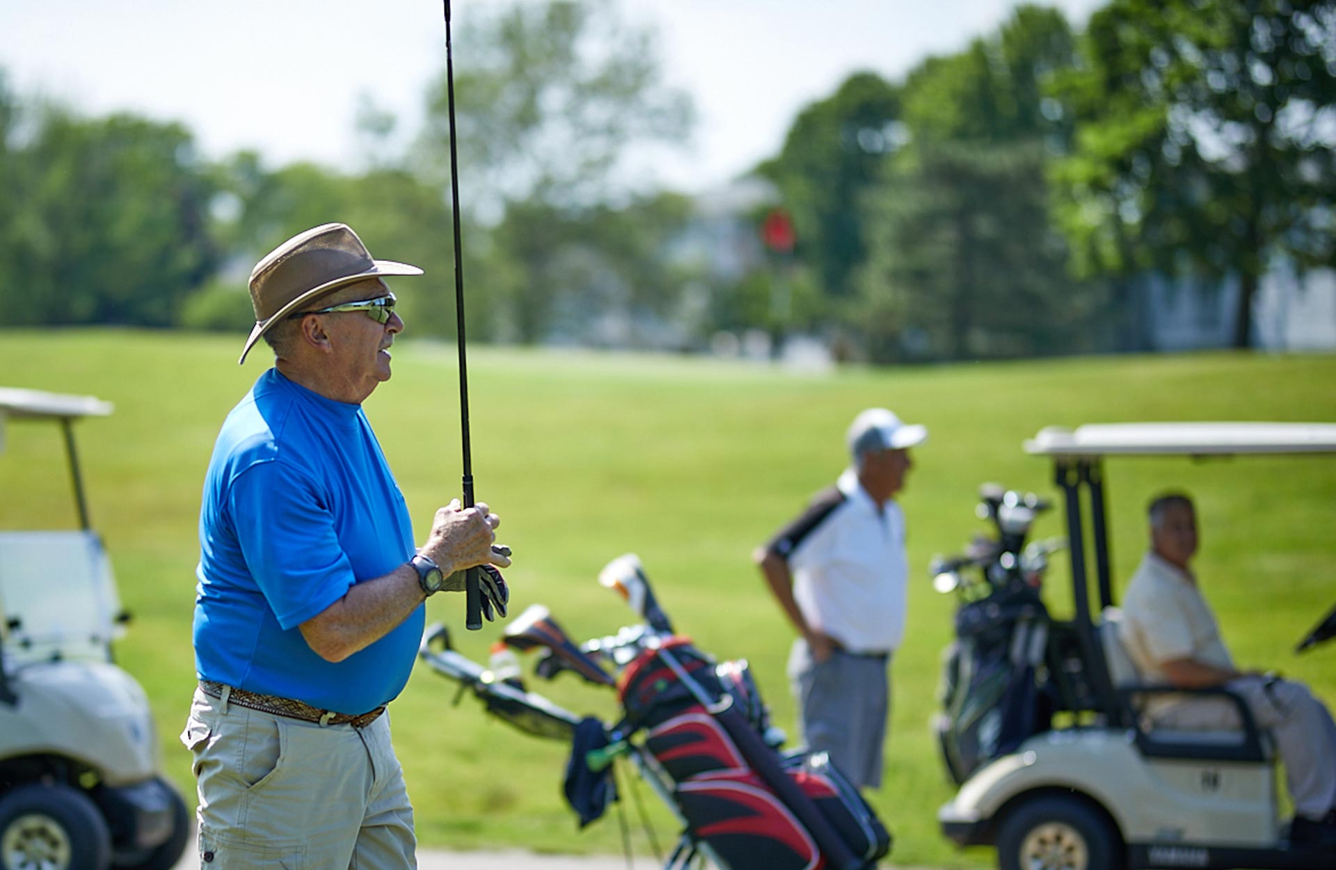 elderly white man carrying golf club on golf course