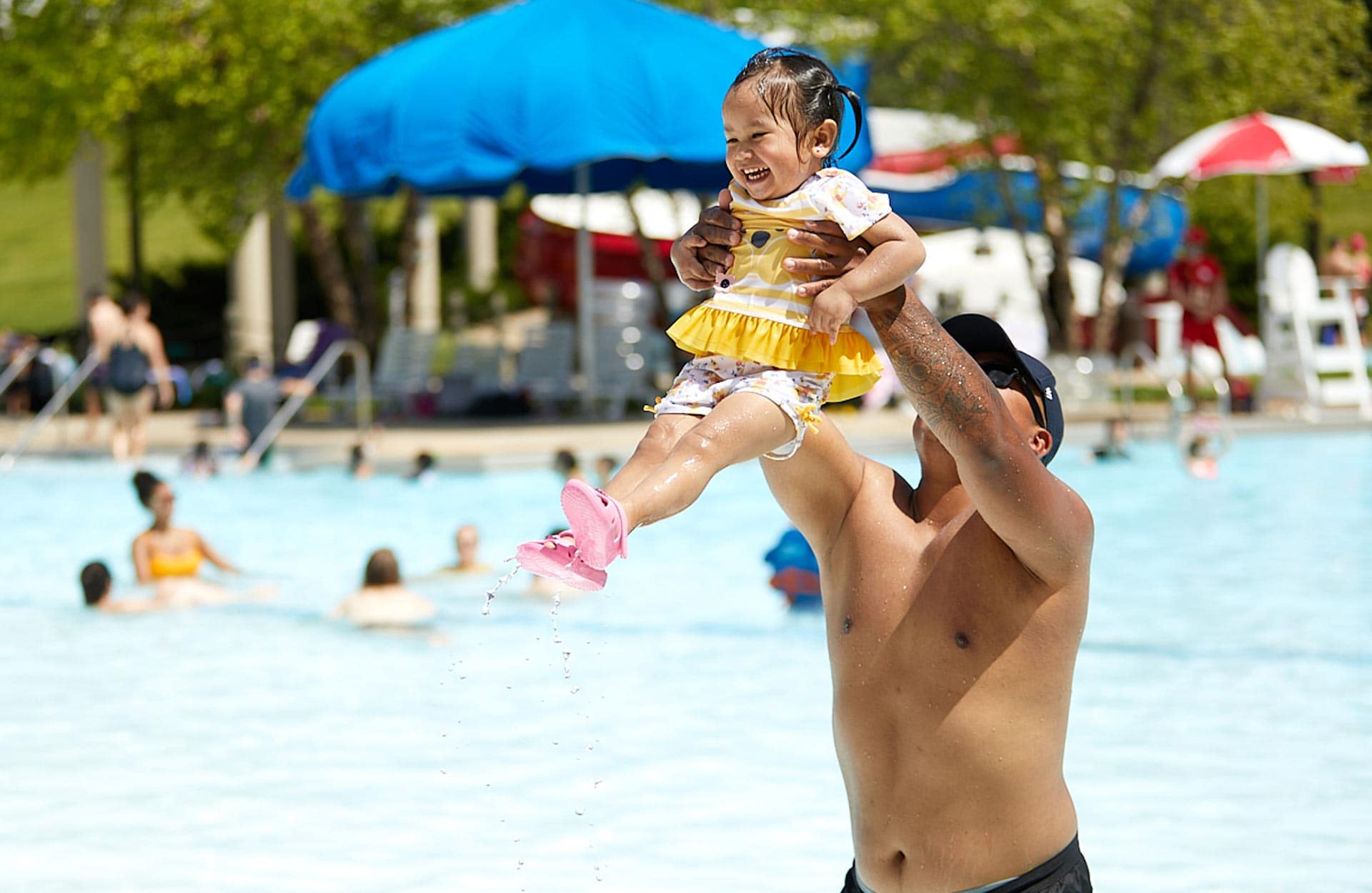 Asian father playing with his baby daughter at Pelican Harbor pool