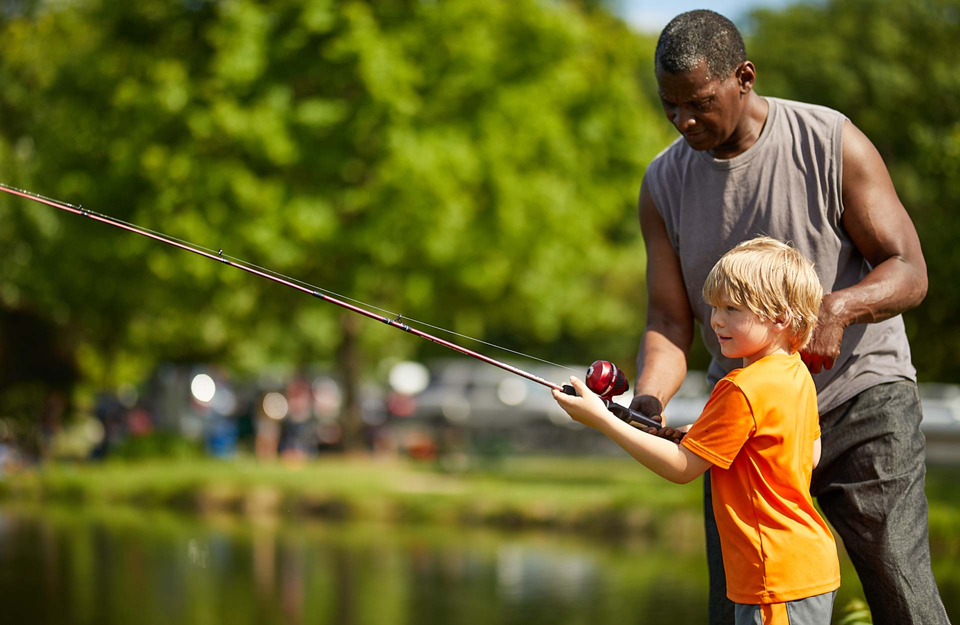 young white boy fishing with his African American grandfather