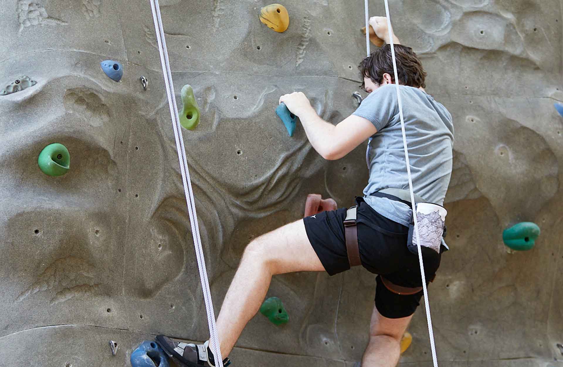 white male teenage boy on rock climbing wall