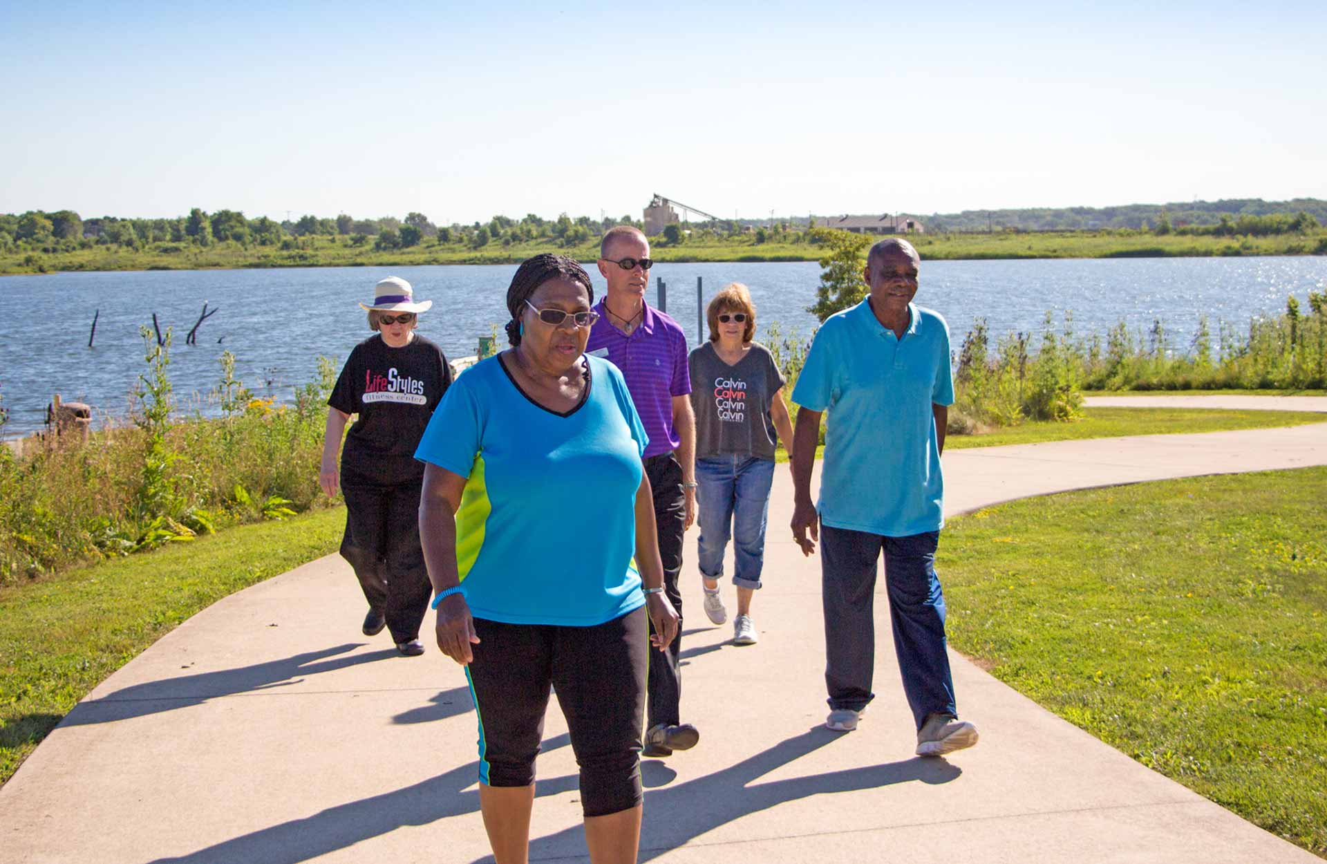 group of elderly adults on walking path next to lake