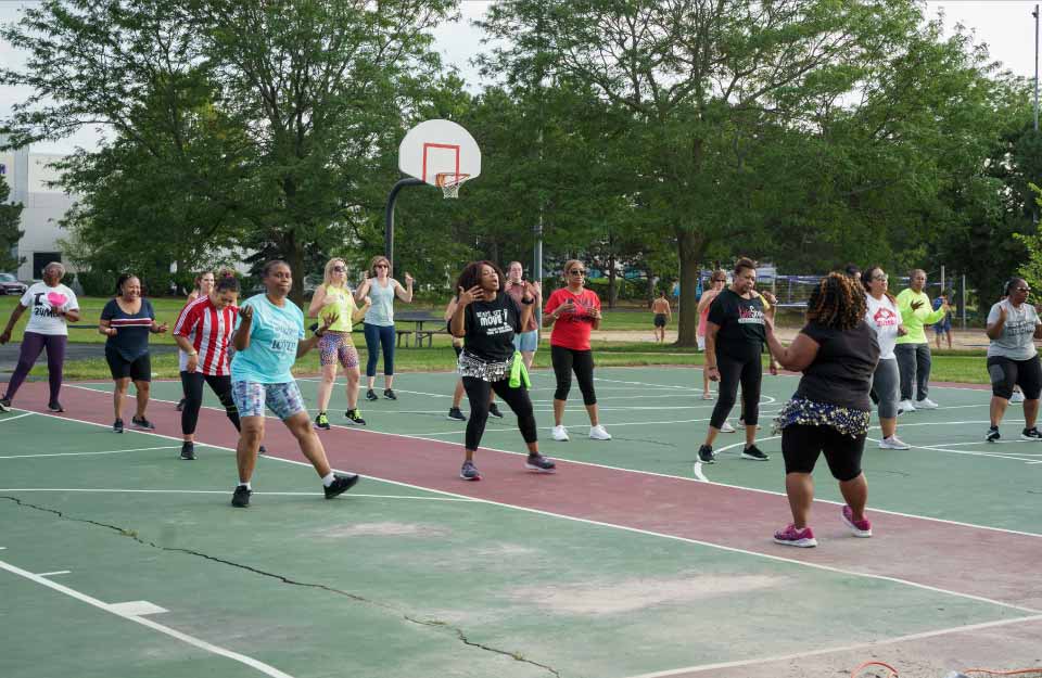 fitness class members doing zumba in the park