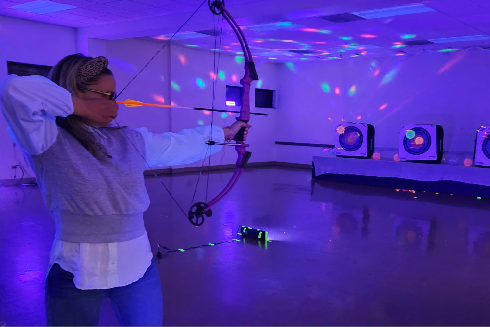 Woman with a bow and arrow in the dark with glow lights