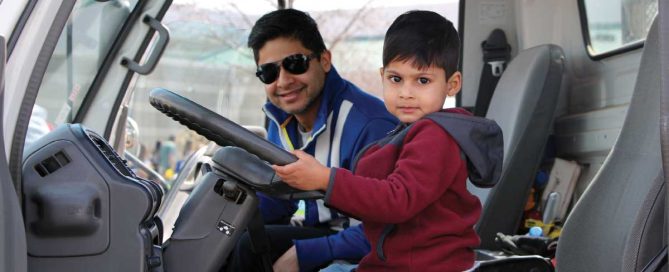 Dark-haired man and his son sitting in a large truck