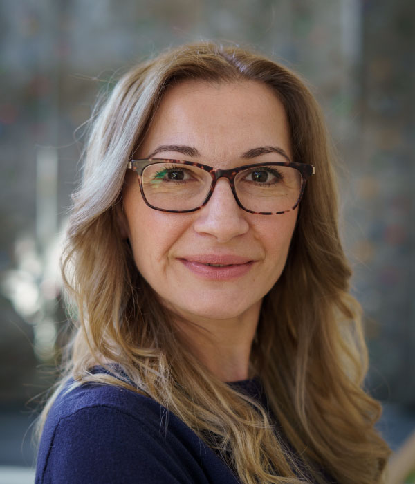 Middle-aged Caucasian female with brown hair and glasses smiling